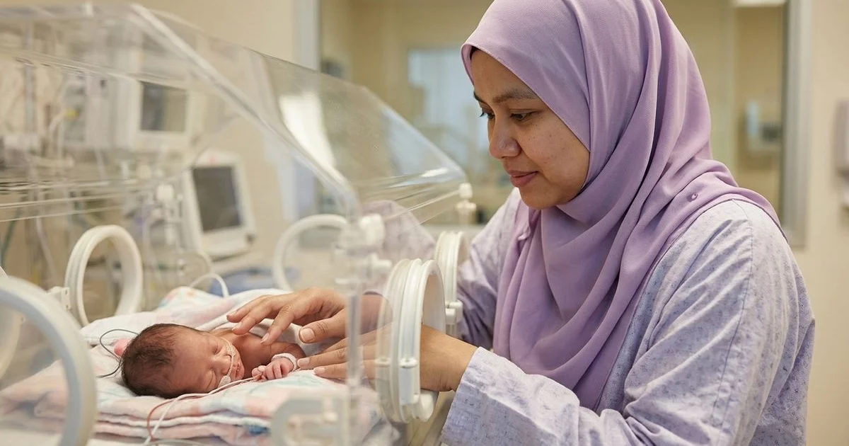 Bayi pramatang dalam inkubator NICU dengan ibu menyentuh dengan lembut